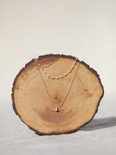 Cargar imagen en el visor de la galería, Collar oro doble con cadena de rosario oro mate y cristal blanco 3x2mm. Cadena de 0,7mm bañada en oro y lágrima facetada 8x5mm, de 37cm con extensión.