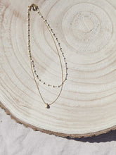 Cargar imagen en el visor de la galería, Collar oro doble con cadena de rosario oro mate y cristal blanco 3x2mm. Cadena de 0,7mm bañada en oro y lágrima facetada 8x5mm, de 37cm con extensión.