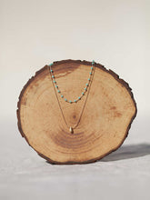 Cargar imagen en el visor de la galería, Collar oro doble con cadena de rosario oro mate y cristal turquesa 3x2mm. Cadena de 0,7mm bañada en oro y lágrima facetada 8x5mm, de 37cm con extensión.