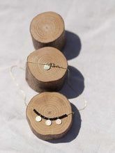 Cargar imagen en el visor de la galería, Collar oro monedas gris, monedas turcas en oro mate de 10x7mm y cristal gris 2mm con cadena sencilla 0,7mm bañada en oro y 37 cm de largo con extensión.