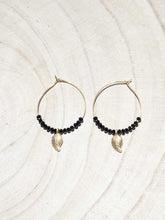 Cargar imagen en el visor de la galería, Pendientes de aro de 30mm bañados en Oro con detalle de hoja 15x7mm Oro mate y cristal facetado de 2mm negro.