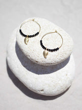 Cargar imagen en el visor de la galería, Pendientes de aro de 30mm bañados en Oro con detalle de hoja 15x7mm Oro mate y cristal facetado de 2mm negro.