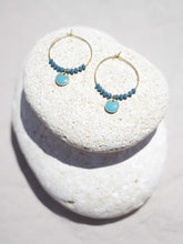 Cargar imagen en el visor de la galería, Aros de 20mm bañados en Oro con detalle de pieza circular esmaltada 8mm azúl y cristal facetado de 2mm verde mar.