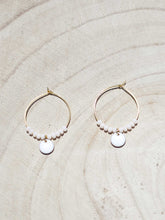 Cargar imagen en el visor de la galería, Aros de 20mm bañados en Oro con detalle de pieza circular esmaltada 8mm blanco y cristal 2mm blanco Opal.
